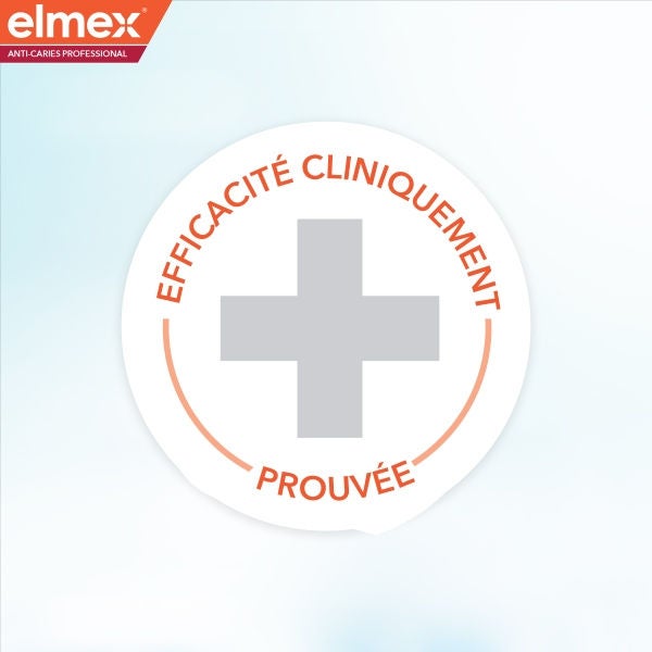Un grand sceau d'approbation médical gris avec une croix centrale, entouré d'une ligne de contour en demi-cercle orange et de la marque elmex