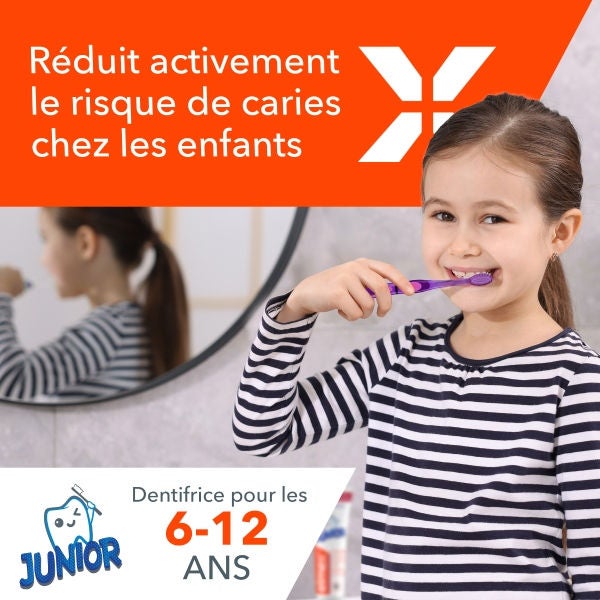 Une jeune fille souriante se brossant les dents avec une brosse à dents violette devant un miroir